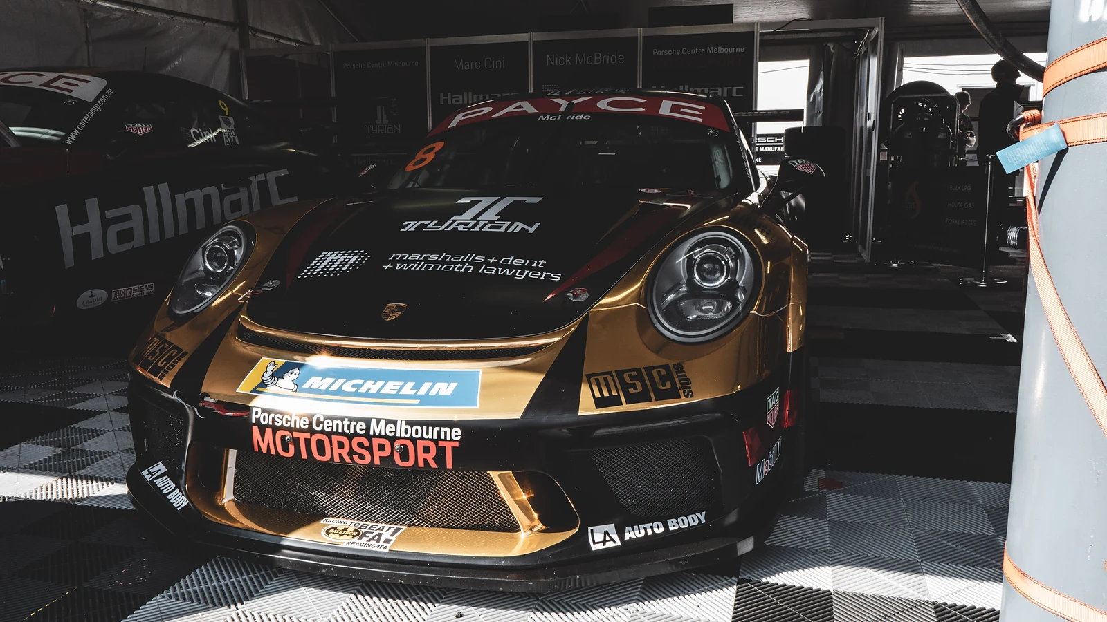 Gold Porsche race car in a pit garage at Bathurst