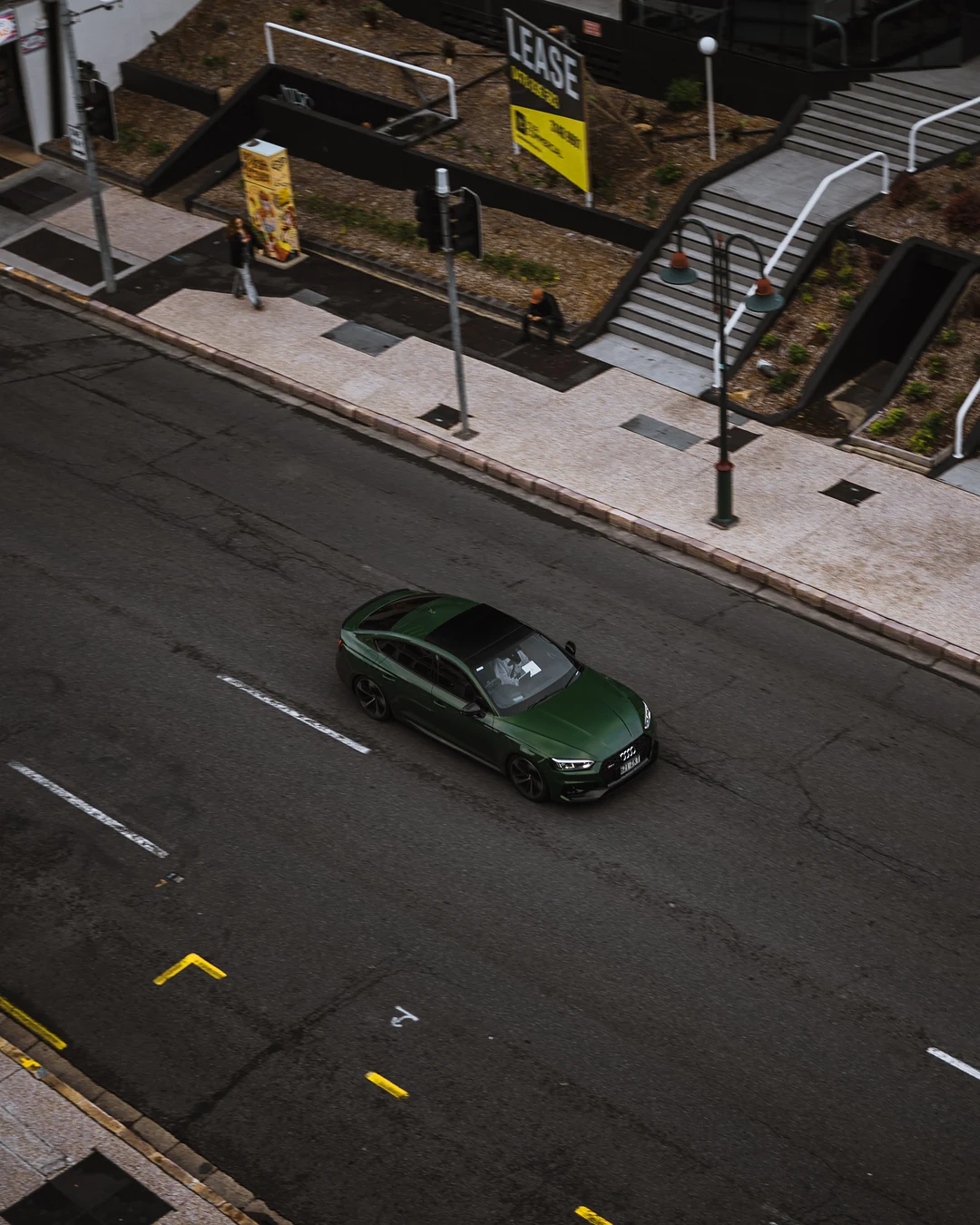 Green car on a city street, shot from directly above