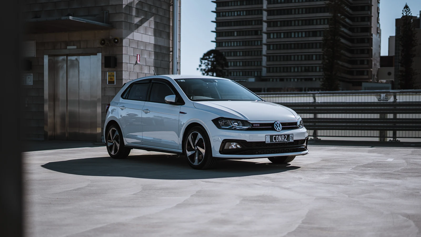 White Volkswagen Polo GTI on a rooftop car park with apartment towers behind