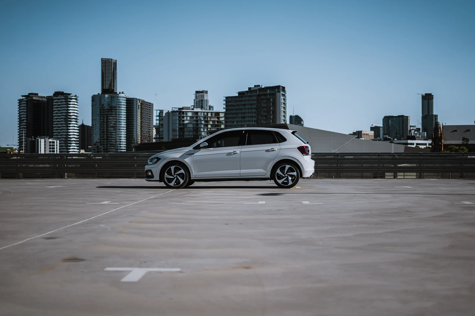 White Volkswagen Polo GTI on a rooftop car park with the Brisbane skyline behind