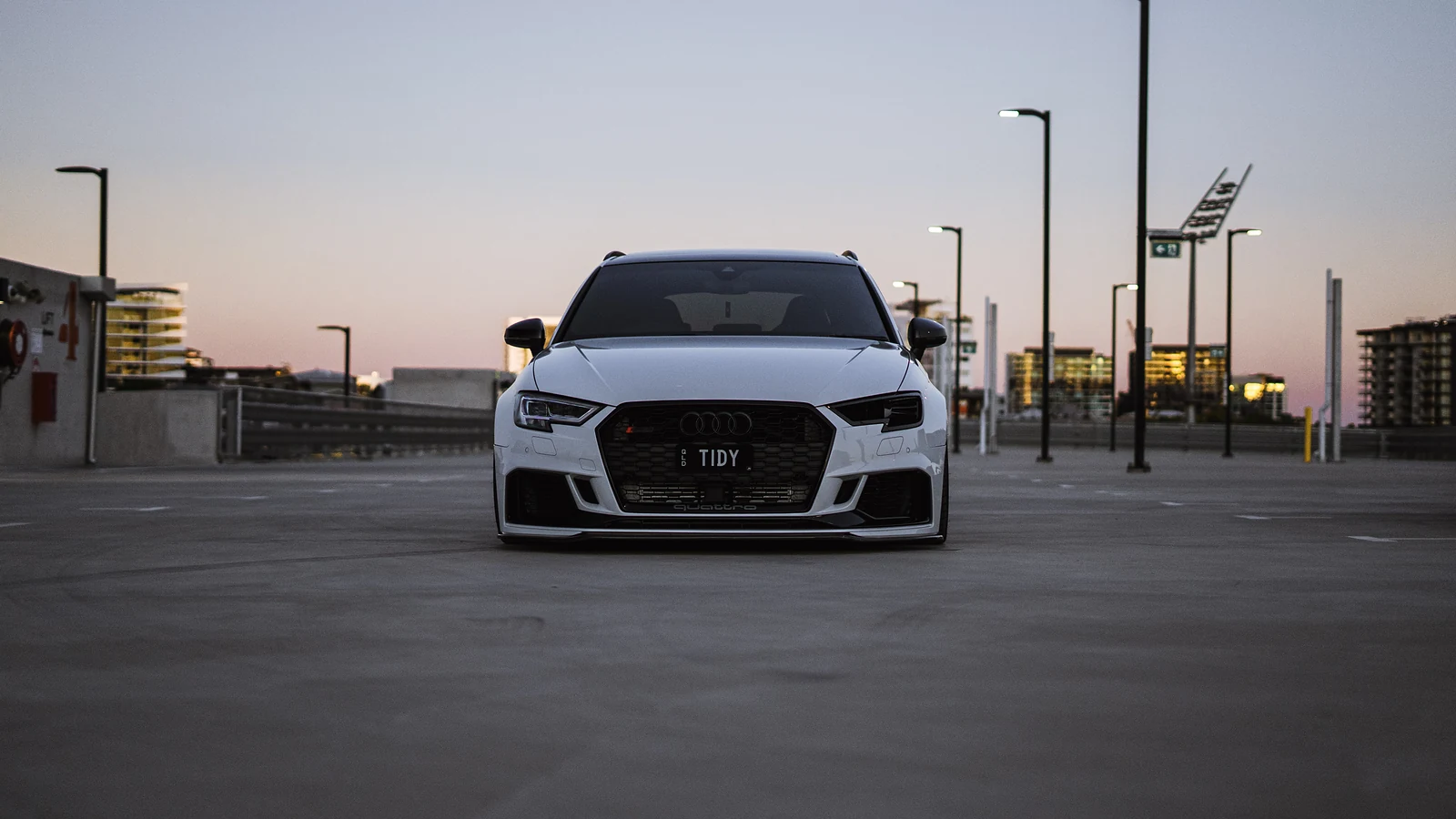 White Audi RS3 head-on on a rooftop car park at dusk