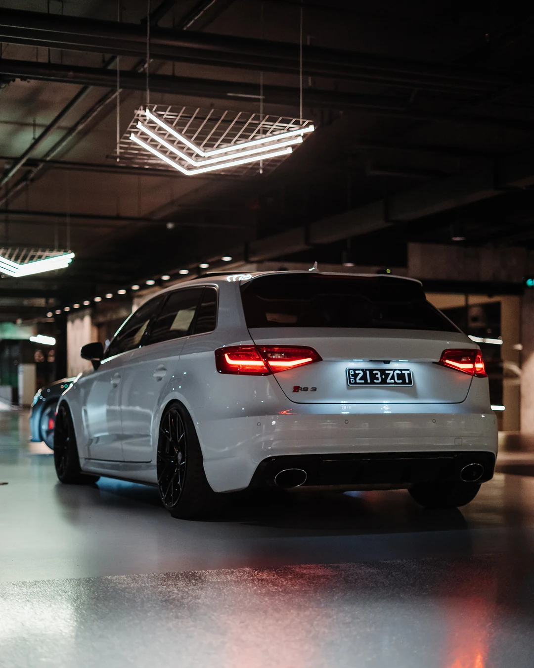 White Audi RS3 from behind in an underground car park, tail lights on