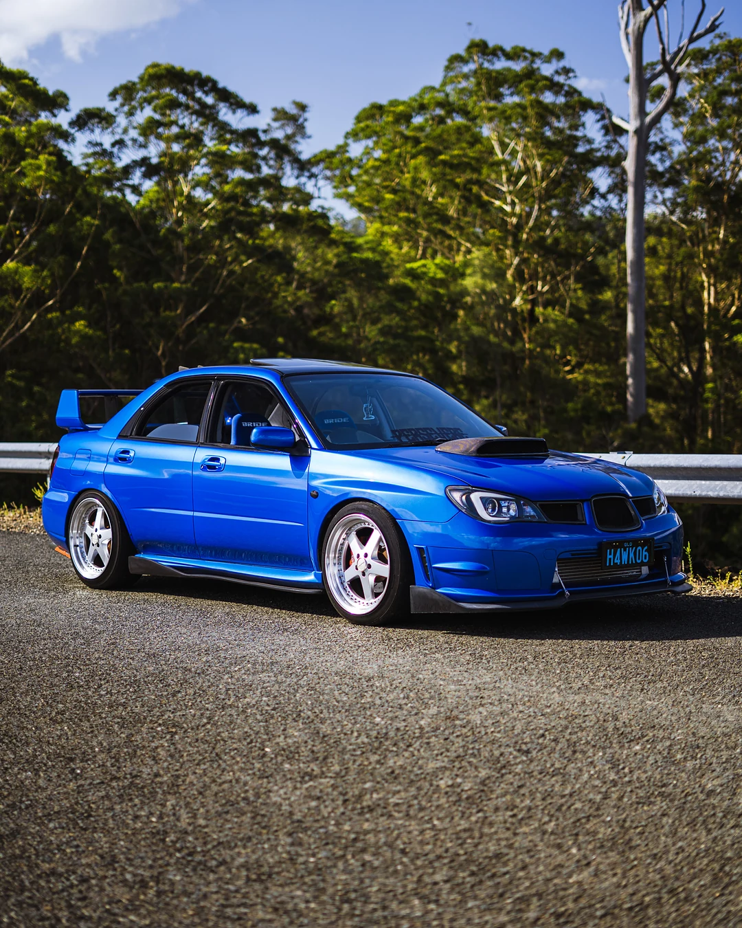 Blue Subaru Impreza WRX parked by a lake with forest behind
