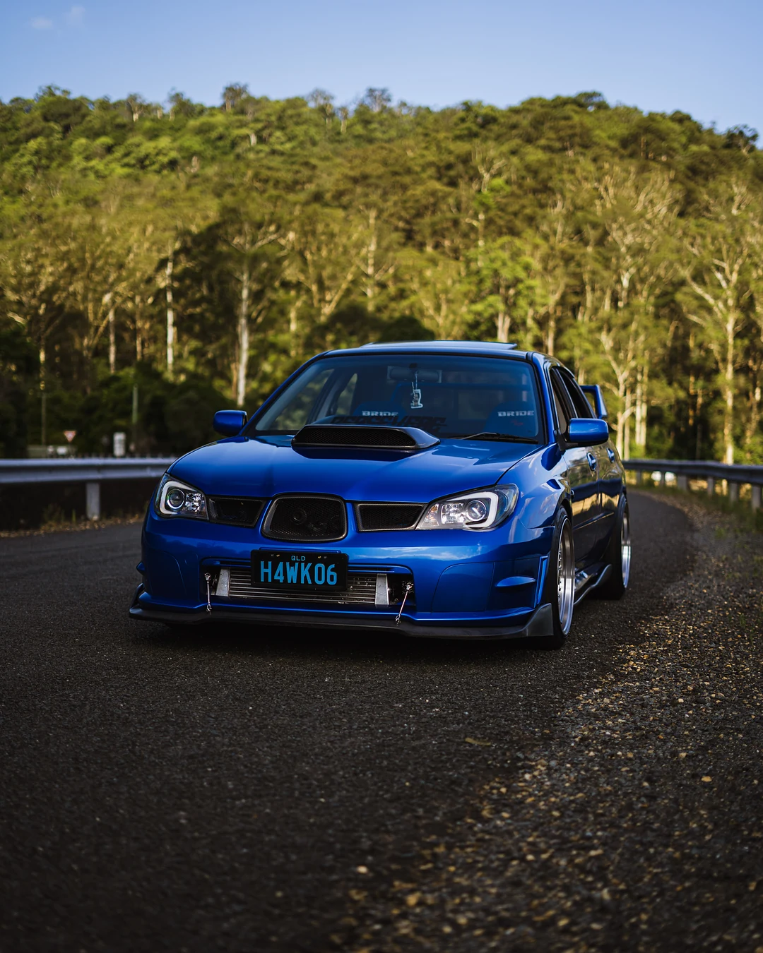 Blue Subaru Impreza WRX head-on in front of forest