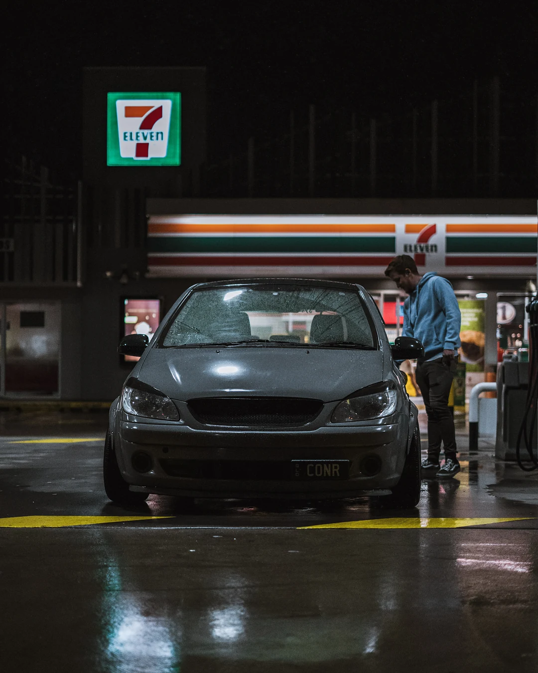 Grey Hyundai Getz at a 7-Eleven fuel bay at night