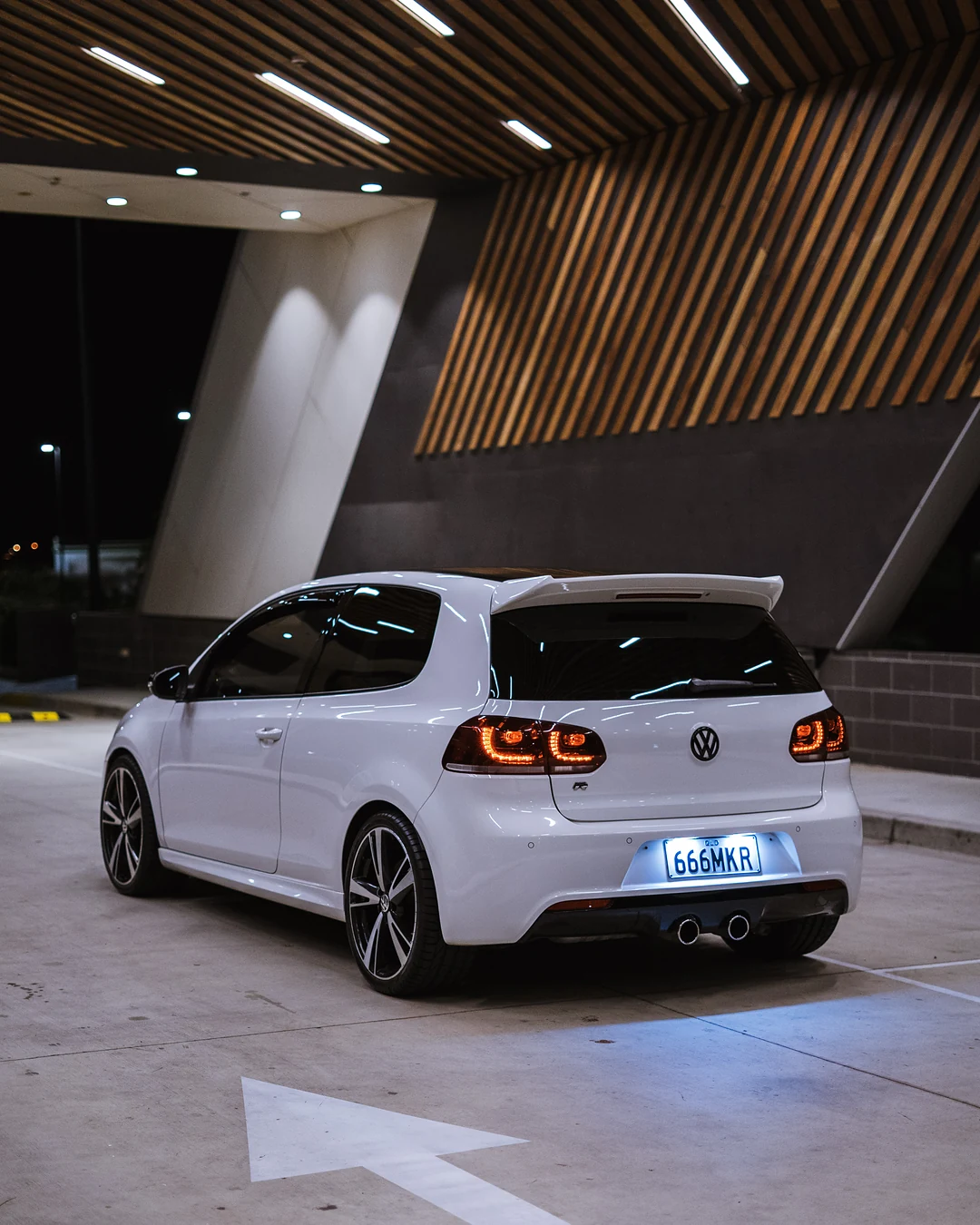 White Golf R from behind under a timber slat ceiling, plates lit