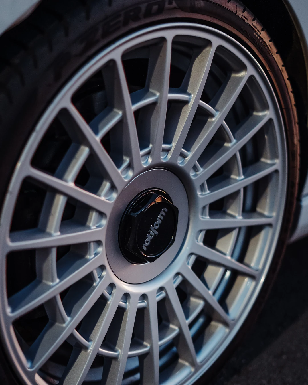 Silver multi-spoke wheel on a white Golf, close up